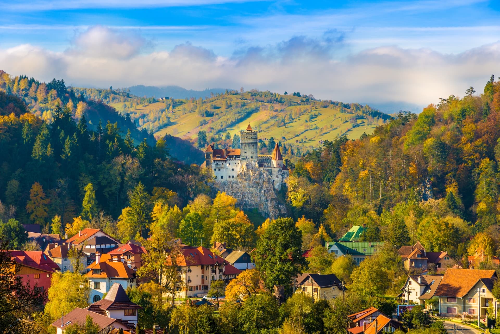 Bran Castle overlooking village and rolling hills with autumn foliage in Transylvania, Romania.