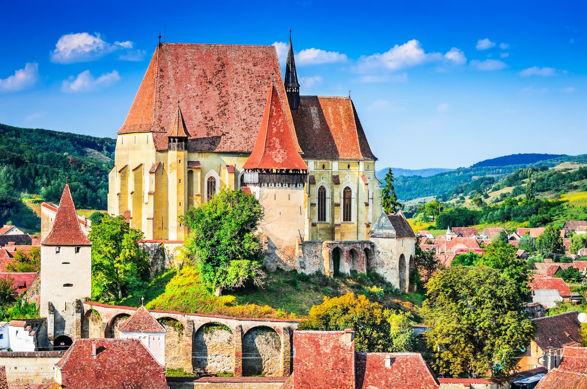 Fortified church with red roof on hill above village in Biertan, Transylvania, Romania.