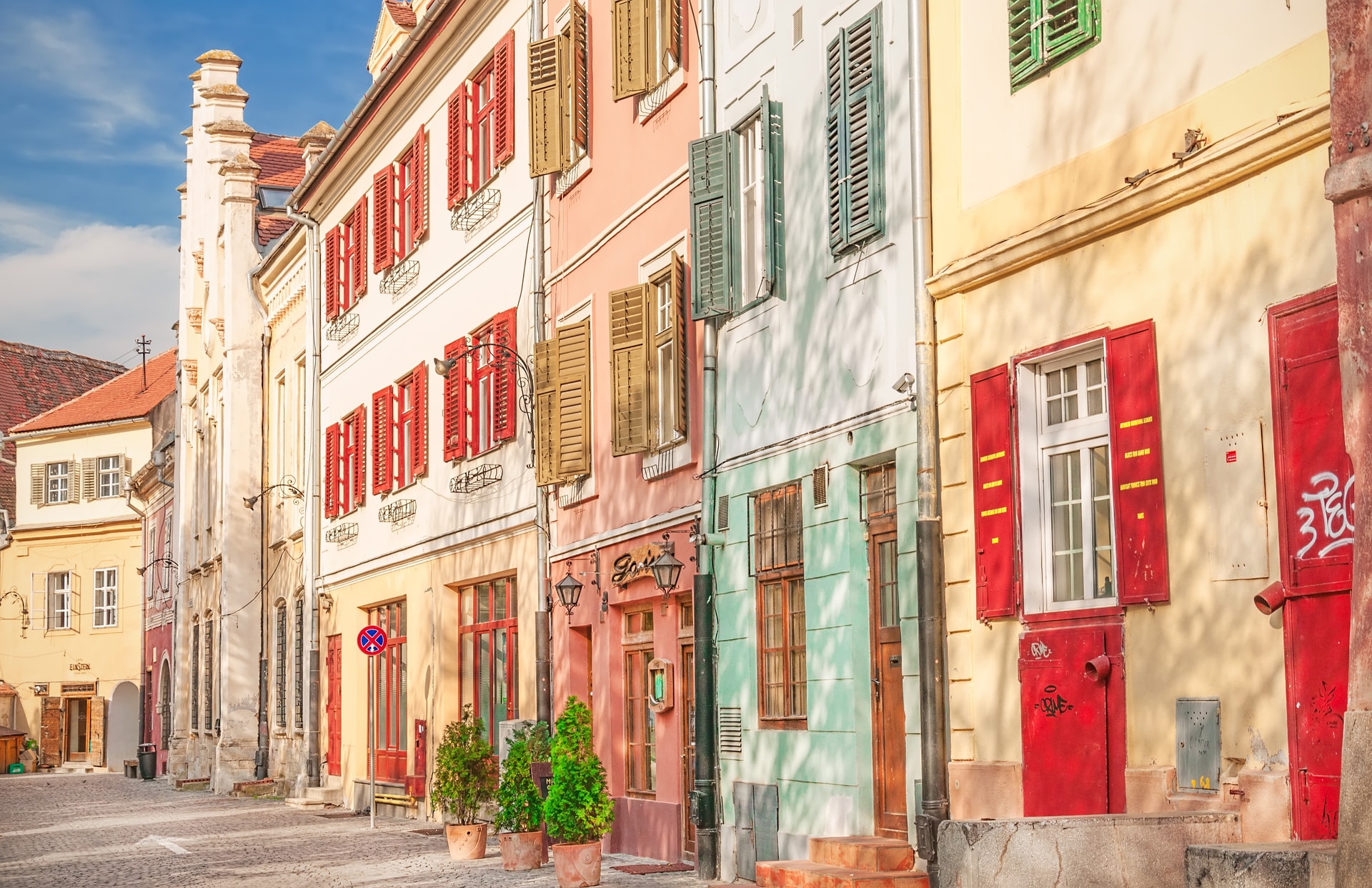 Colorful historic houses with shutters lining a cobblestone street in Sibiu, Transylvania, Romania.